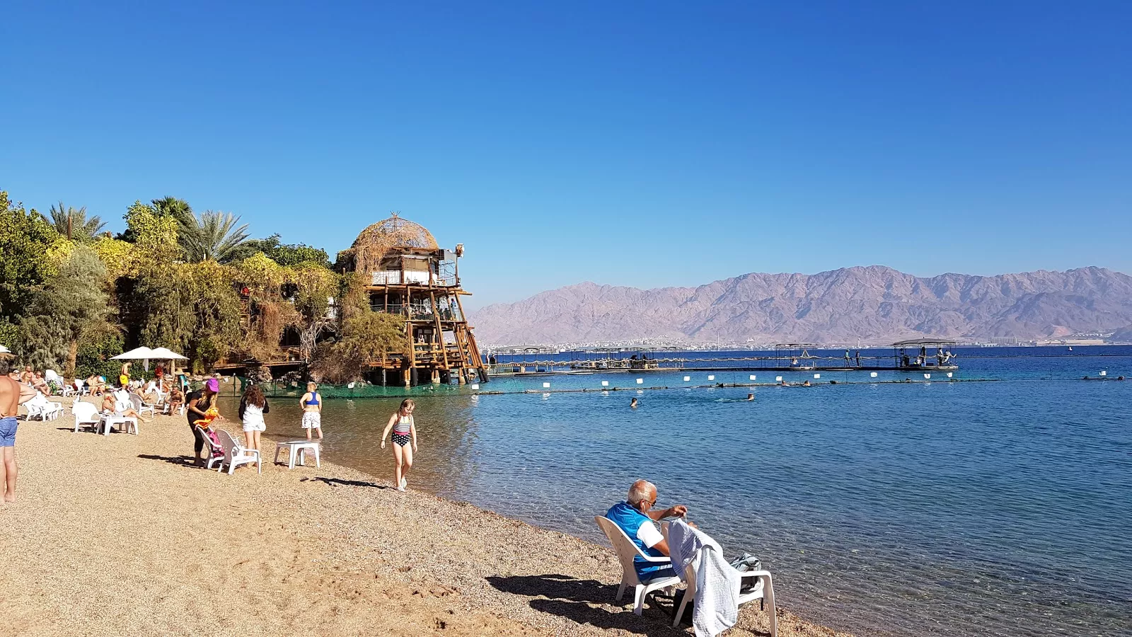 Illustration: family silhouettes on a sandy beach near turquoise water